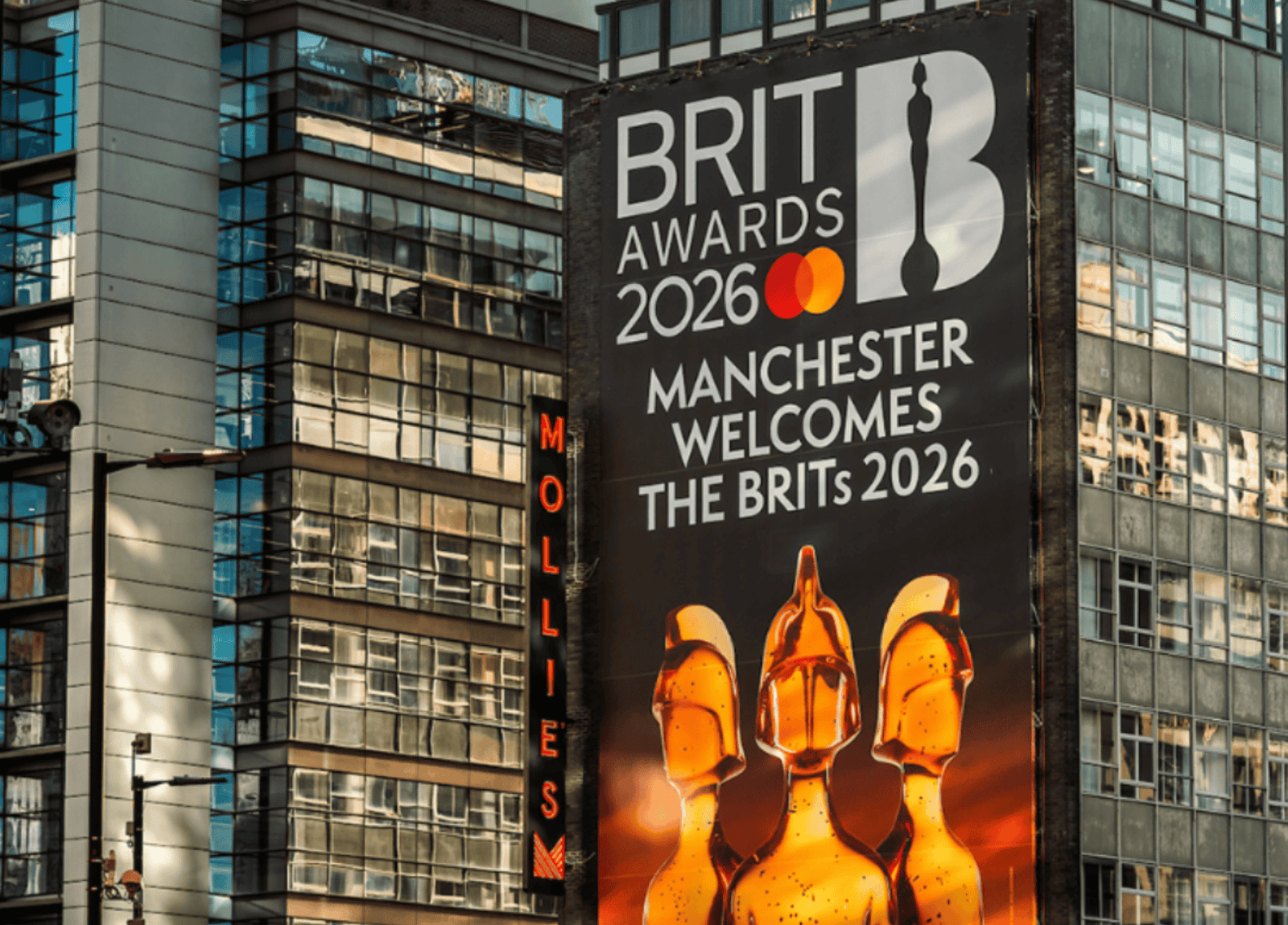A BRIT Awards 2026 billboard on a Manchester building reading Manchester welcomes the BRITs 2026